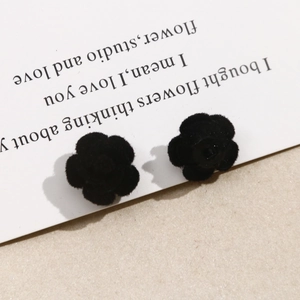 Detalle de pendientes de rosa de terciopelo negro con textura suave flocada