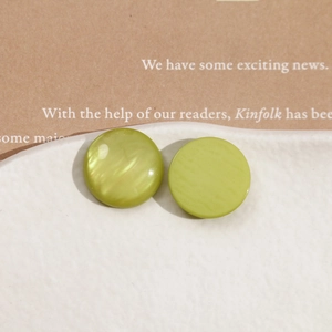 Macro shot of lime green pearlescent resin cabochons on a white textured ceramic dish