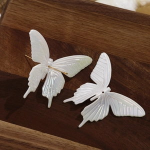 Macro detail of iridescent butterfly charms on a wooden tray for DIY hair accessories