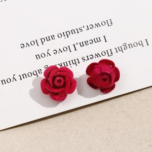 Detalle de pendientes de rosas de terciopelo rojo y metal sobre tarjeta vintage