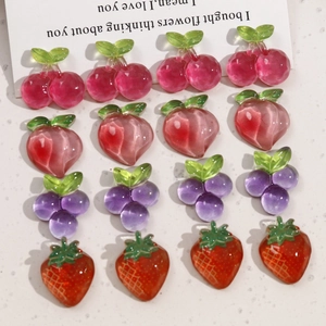 Flat lay of transparent resin fruit charms including cherry, peach, grape and strawberry