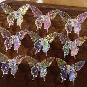 Macro detail of nine 3D iridescent butterfly resin charms for DIY hair accessories