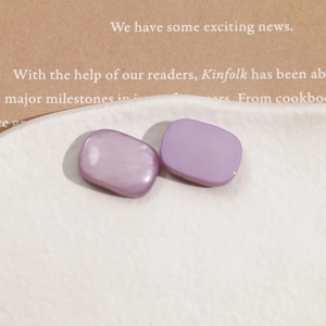 Macro shot of two lavender resin rectangle charms on a textured white ceramic tray