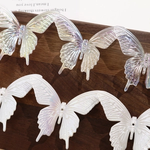 Macro view of 3D iridescent butterfly resin charms for DIY hair accessories on wood