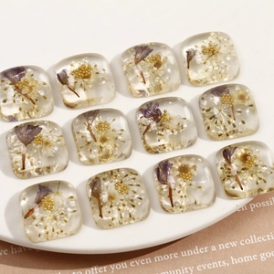Détail de breloques carrées en résine avec fleurs séchées violettes et perles pour bijoux DIY