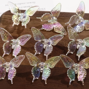 Macro detail of nine translucent aurora resin butterfly charms on dark wood background