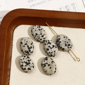 Macro-opname van ovale dalmatiër jaspis kralen en gouden metalen pinnen voor DIY sieraden