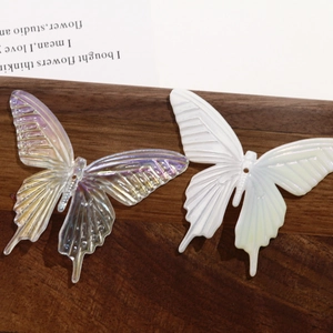 Iridescent and pearl acrylic butterfly charms for DIY jewelry on a wooden tray
