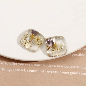 Boucles d'oreilles carrées en résine avec fleurs séchées violettes et perles sur assiette