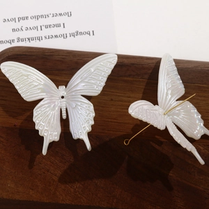 Detailed view of iridescent resin butterfly charms with metal pins on dark wood