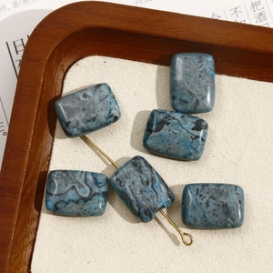 Macro-opname van blauwe marmeren rechthoekige kralen met gouden naald voor DIY-sieraden