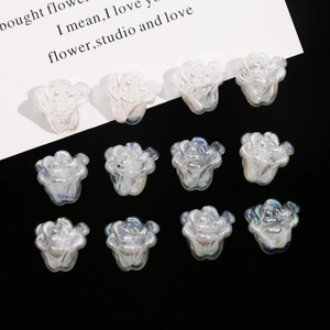 Macro view of twelve pearlescent acrylic rose beads arranged on black velvet background