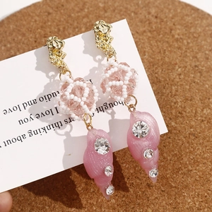 Detail view of handmade beaded earrings with pink conch shell pendant and crystals