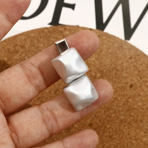 Close-up of geometric silver earrings with iridescent pearly squares and metal base