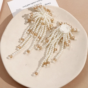 Macro detail of long tassel earrings made of white pearls and amber crystal beads