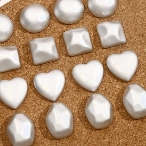 Detailed view of iridescent pearl white DIY jewelry charms in various geometric shapes