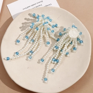 Detail of fan-shaped fringe earrings with white pearls and sky blue crystal beads