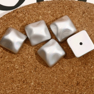 Macro detail of square iridescent silver DIY charm accessory with a single center hole