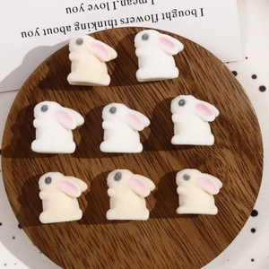 Macro view of eight cute flocked white rabbit beads for DIY jewelry and accessory making
