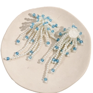 Elegant white pearl and sky blue beaded long tassel fringe drop earrings on a ceramic dish