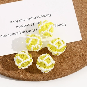 Macro detail of 5 yellow crystal beads with white hand-woven mesh for DIY jewelry making