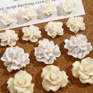 Macro view of white flocked rose and carnation flower charms on a cork background