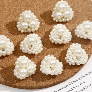 Detailed view of triangular pearl cluster flower charms on a rustic cork display platform