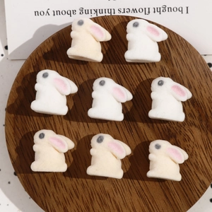 Detail view of cute flocked bunny charms for DIY jewelry in white and beige tones