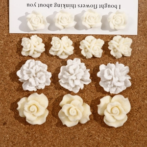 Macro view of 13 pieces cream white 3D resin floral charms on cork background for DIY crafts