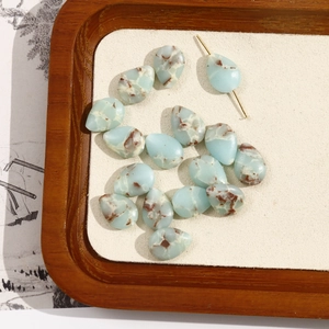 Macro shot of blue teardrop stone beads with natural texture on a wooden tray for DIY jewelry
