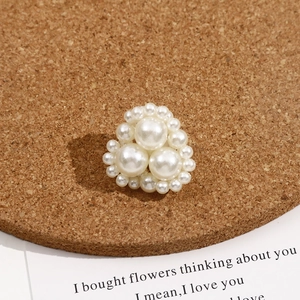 Macro detail of triangle pearl beads with white imitation pearls on cork display board