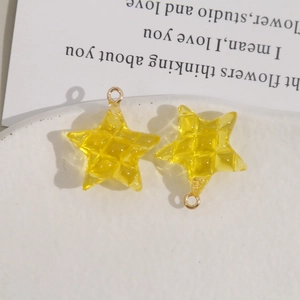 Macro-opname van gele sterhangers met ruittextuur en metalen ringen voor DIY-sieraden