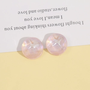 Macro detail of round shimmering pink resin charms with celestial starburst reflection