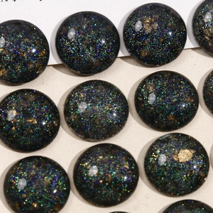 Macro shot of black galaxy resin cabochons with colorful glitter for DIY crafts