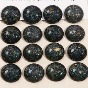 Macro shot of 16 starry resin cabochons with gold foil and teal glitter for DIY jewelry