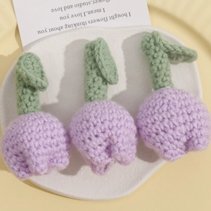 Handmade crochet light purple tulip brooches set of three on a white ceramic tray