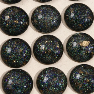 Macro view of black glitter cabochons with gold sequins for DIY jewelry making