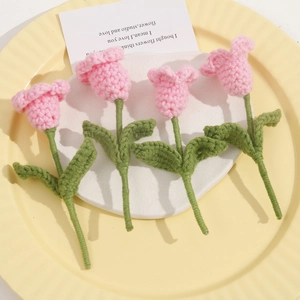 Close-up of four handmade crochet tulip flowers in pink and green on a decorative tray
