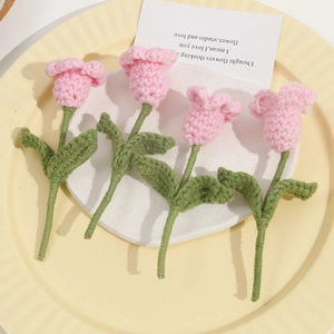 Detail of pink hand-knitted crochet tulip flowers with green stems and leaves