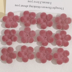 Détail de douze breloques fleurs en acrylique rose floqué pour création de bijoux