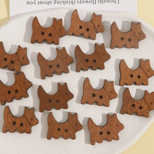 Close-up of 14 pieces of brown wooden puppy-shaped two-hole buttons in a white tray