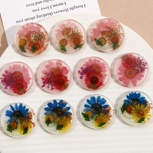Macro shot of assorted round resin pendants with embedded real dried flowers for DIY jewelry