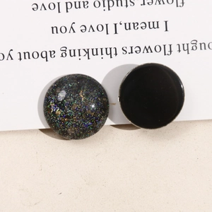 Macro view of round glitter starry sky and black enamel charms with silver metal edges
