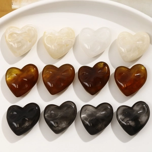 Macro detail of resin heart beads with ink marble texture in neutral earthy tones
