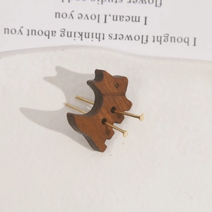 Macro detail of dog-shaped wooden charm featuring a smooth texture and golden metal pins