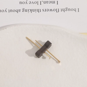 Detail of wooden butterfly charm with crossed gold pins on a white decorative plate