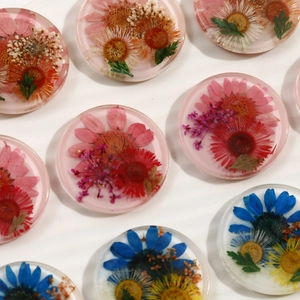 Macro detail of transparent resin charms with embedded colorful natural dried flowers