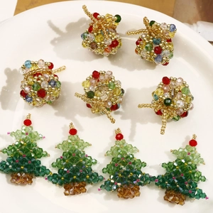 Handmade beaded Christmas tree and colorful sphere pendants in a white ceramic dish