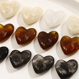 Macro detail of heart-shaped resin charms with marble textures and a polished finish
