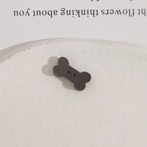 Macro view of black bone-shaped wooden buttons with two holes for DIY sewing projects